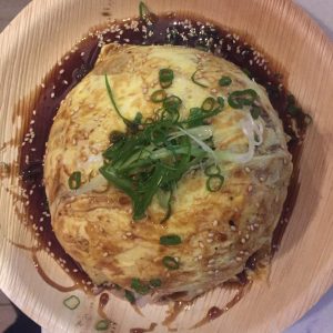 Arroz salteado al wok con pollo, verduras, vino blanco, semillas de ajonjolí, cubierto con una delicada tortilla y bañado en salsa teriyaki.